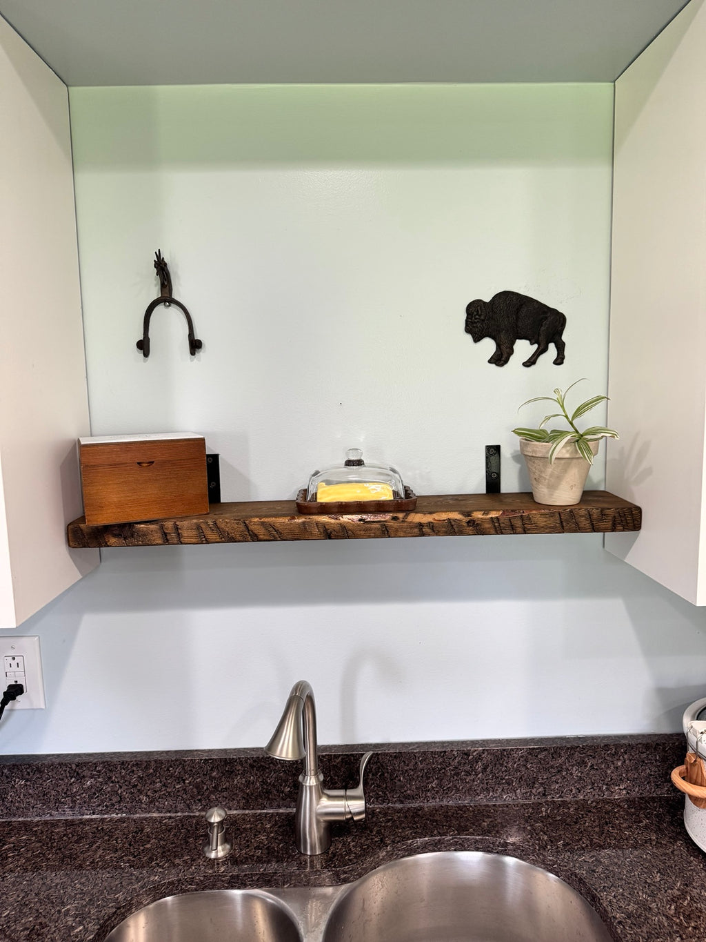 Dark walnut floating shelf above sink with bison wall art